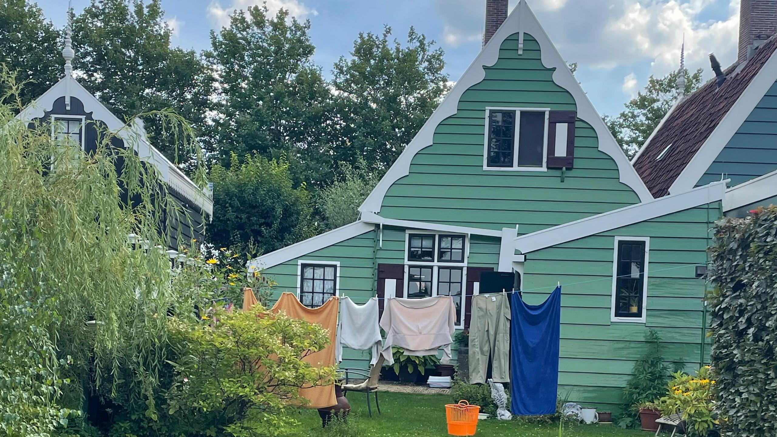 The garden of one of the houses in the village, which is very pretty and quaint and is painted green and white. There is clothes washing hanging on a line out the front.