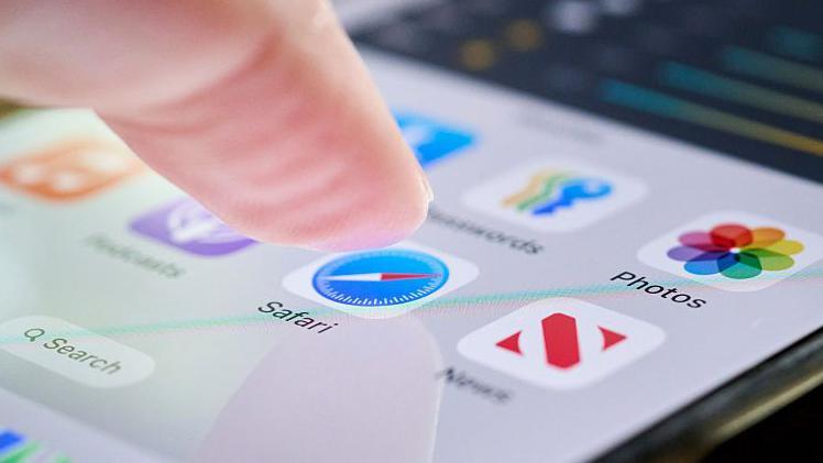 A finger about to press the safari app on a smarthphone