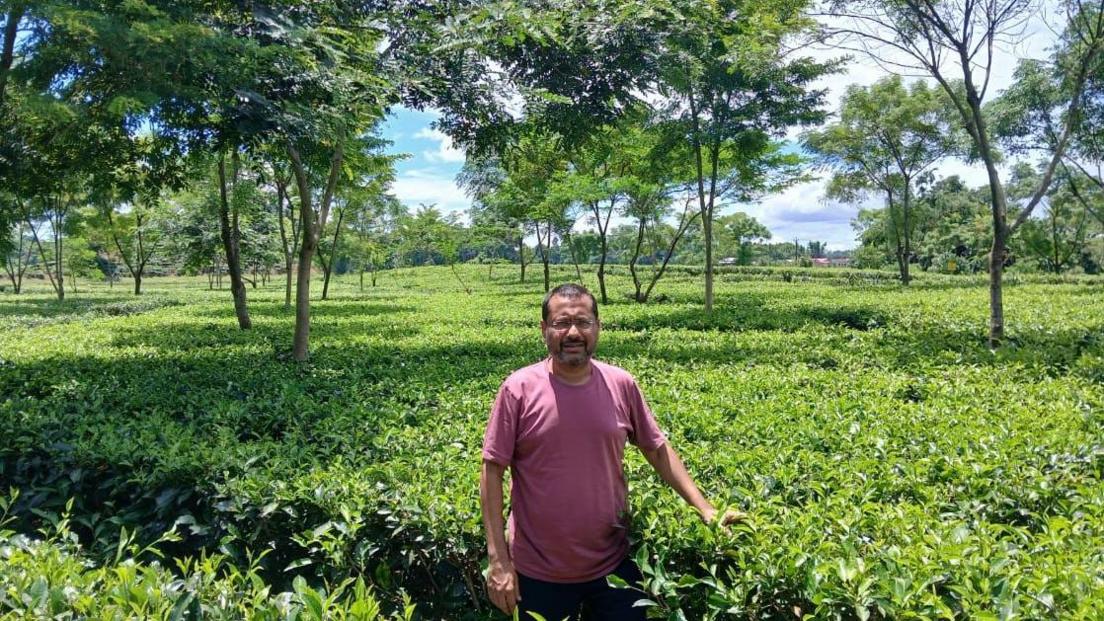 Dressed in a plain red t-shirt, Asian Tea and Exports Director Mohit Agarwal is seen posing for a photo in the middle of a large tea plantation in Assam, India.